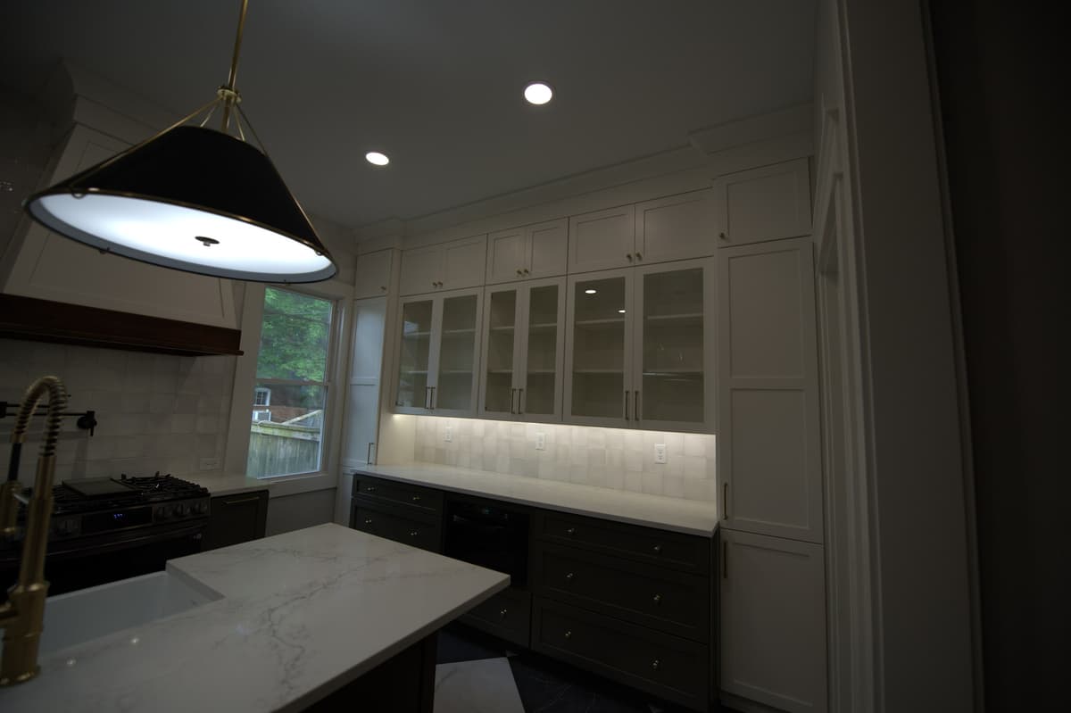 Kitchen with brass pendants over counter, white upper cabinets