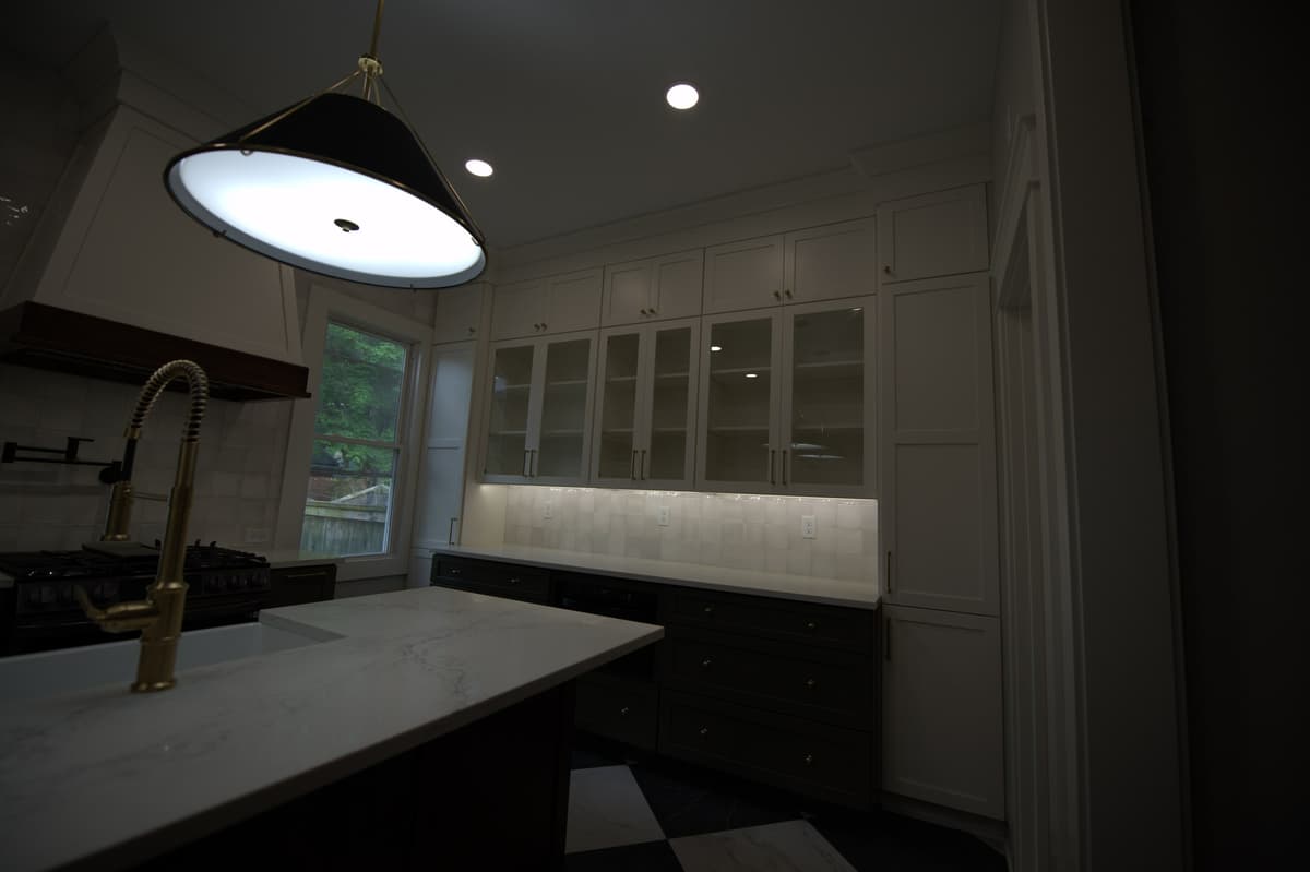Kitchen counter with brass faucet, glass upper cabinets